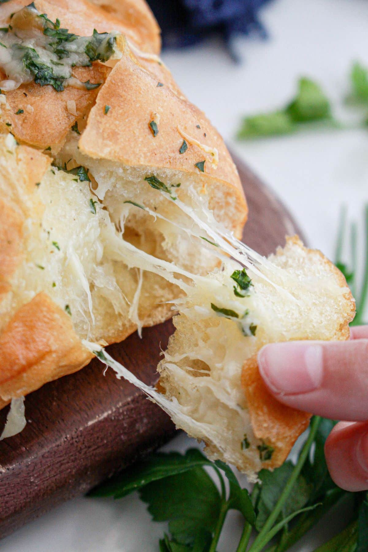 piece of cheesy garlic bread being removed from the loaf of bread.