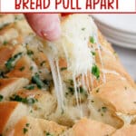 piece of cheesy garlic bread being removed from the loaf of bread.