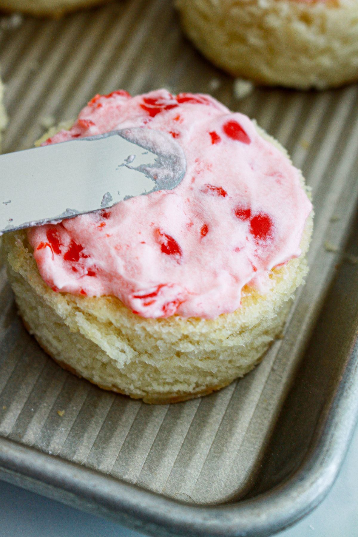 cherry frosting being spread on top of the mini cake.