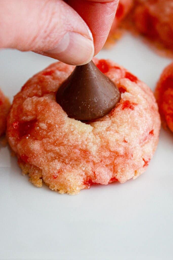 Hershey Kiss being added to the top of a cookie.