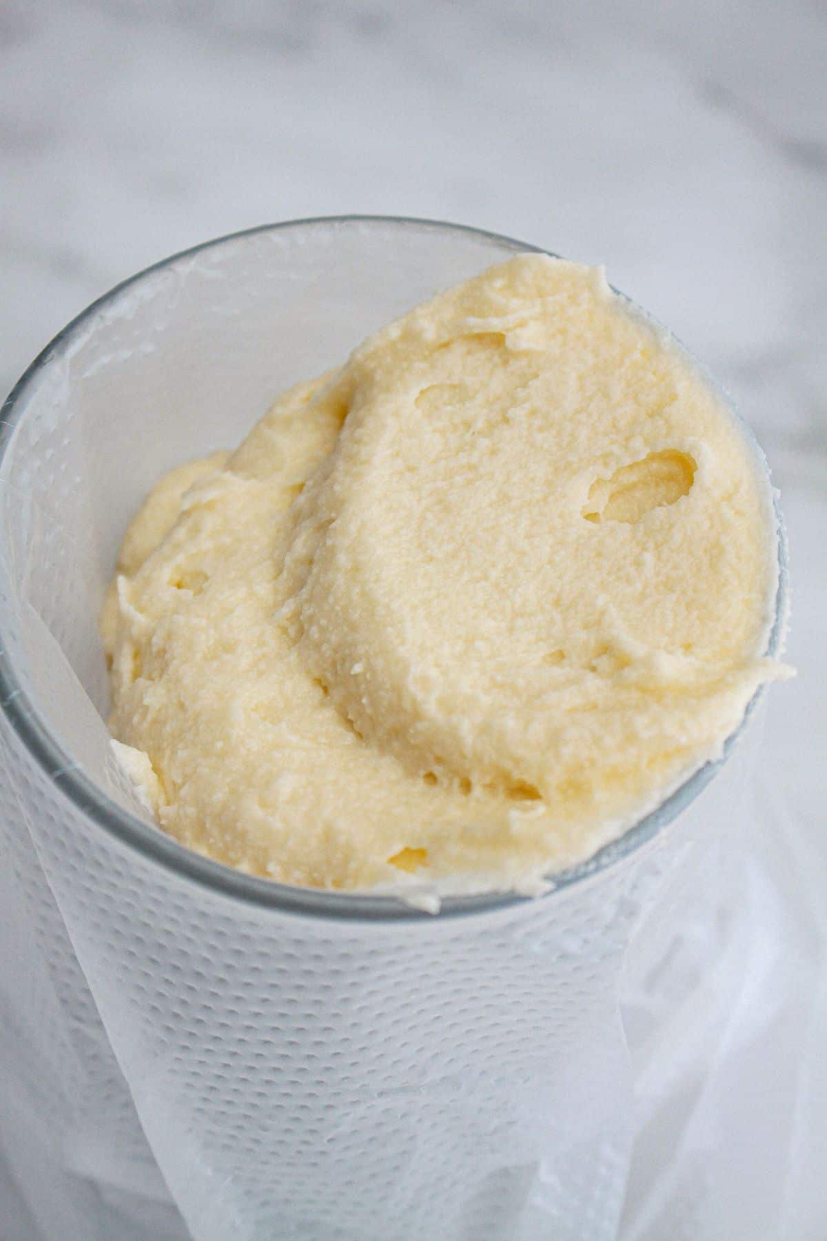 frosting being added to a piping bag in a glass.