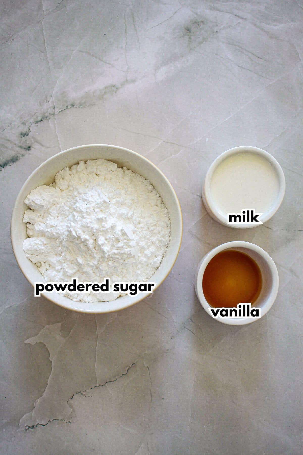 bowls of powdered sugar, milk, and vanilla on a counter.
