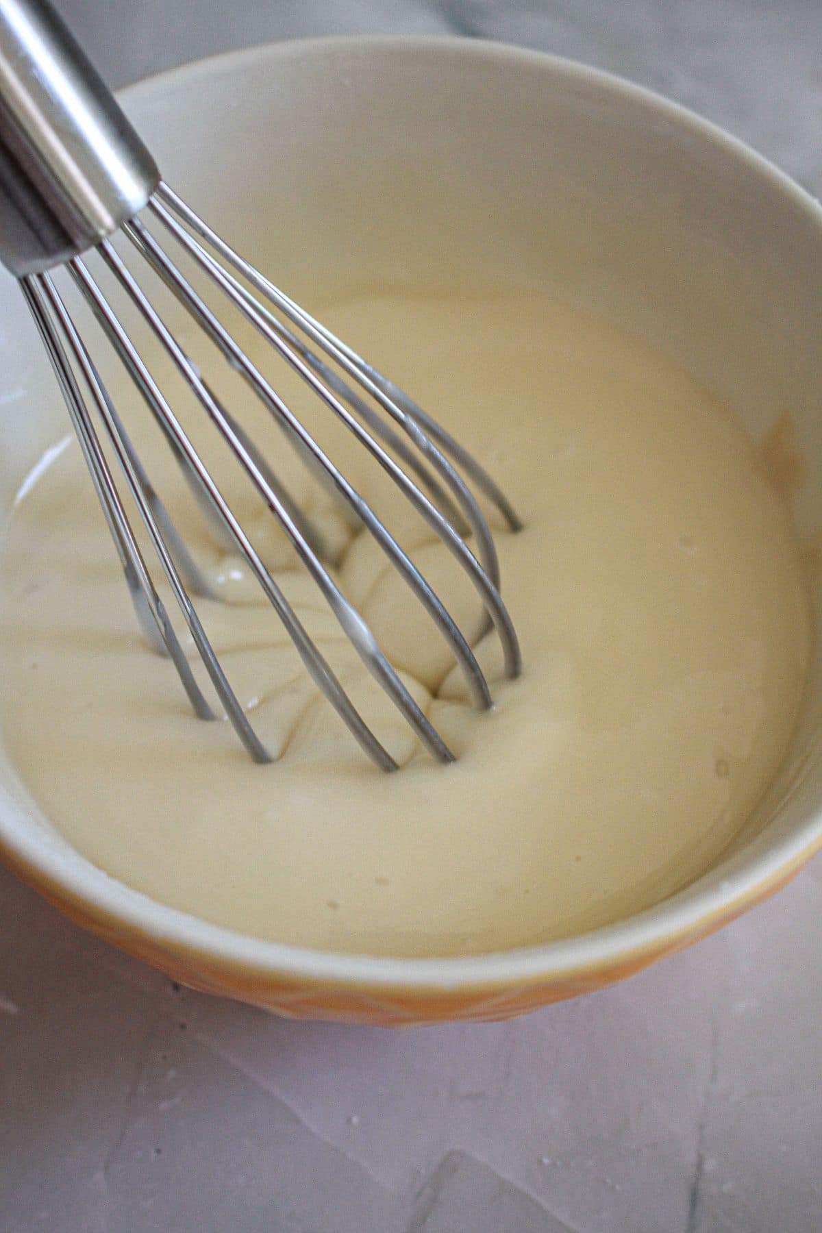 glaze being mixed in a mixing bowl with a whisk.