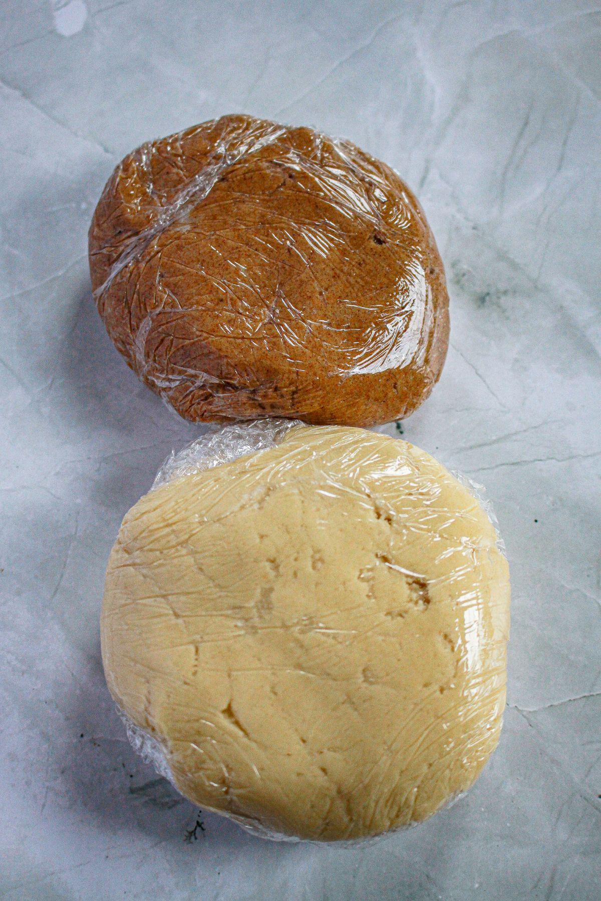 two cookie dough balls wrapped in plastic wrap ready for the fridge.