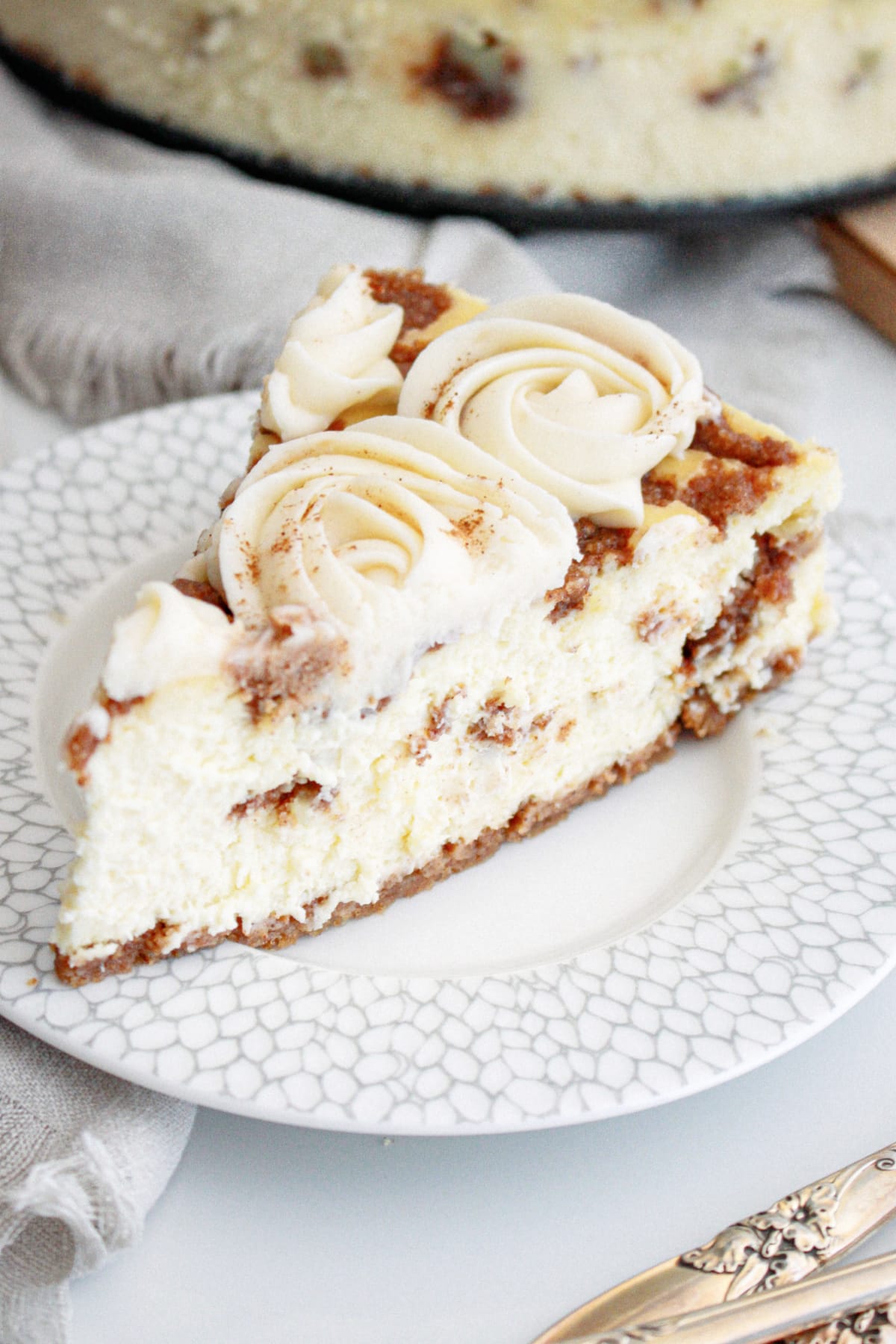 slice of cinnamon roll cheesecake on a small plate.