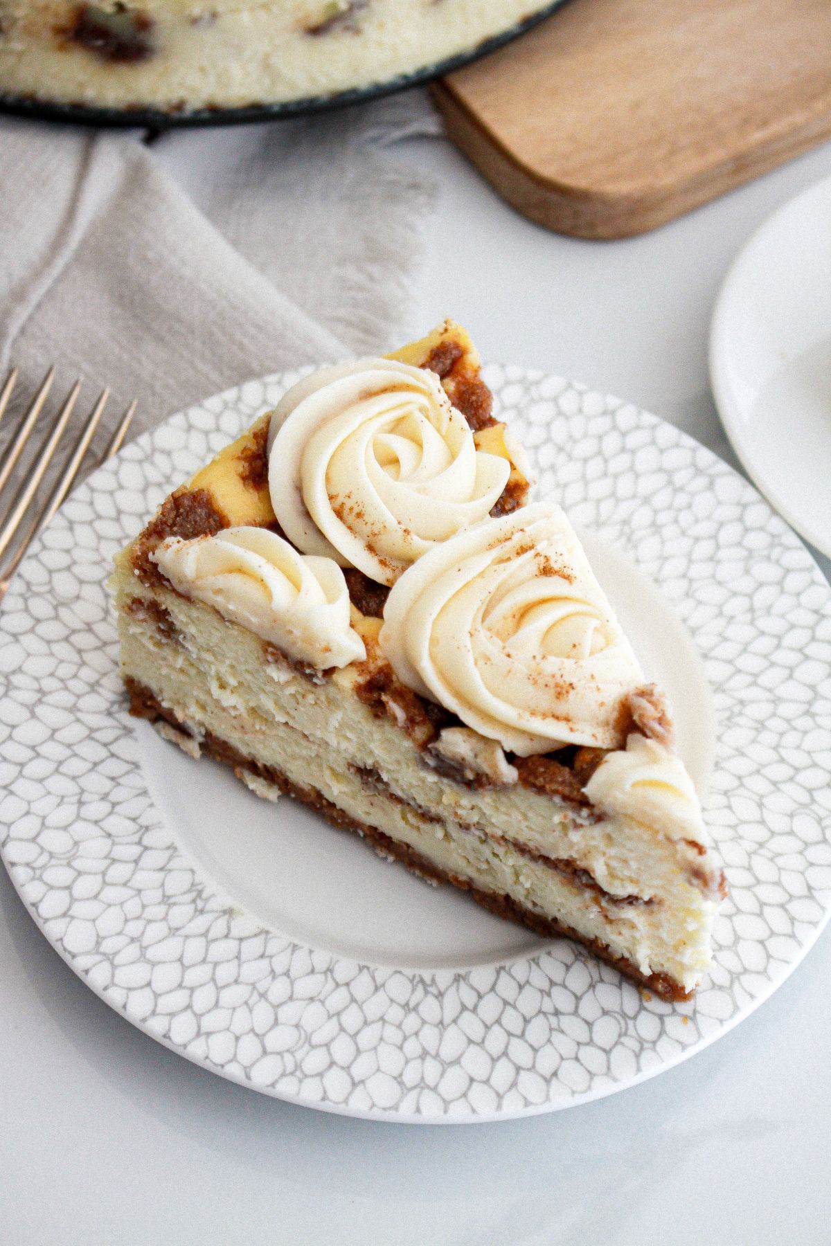 slice of cinnamon roll cheesecake on a small plate.