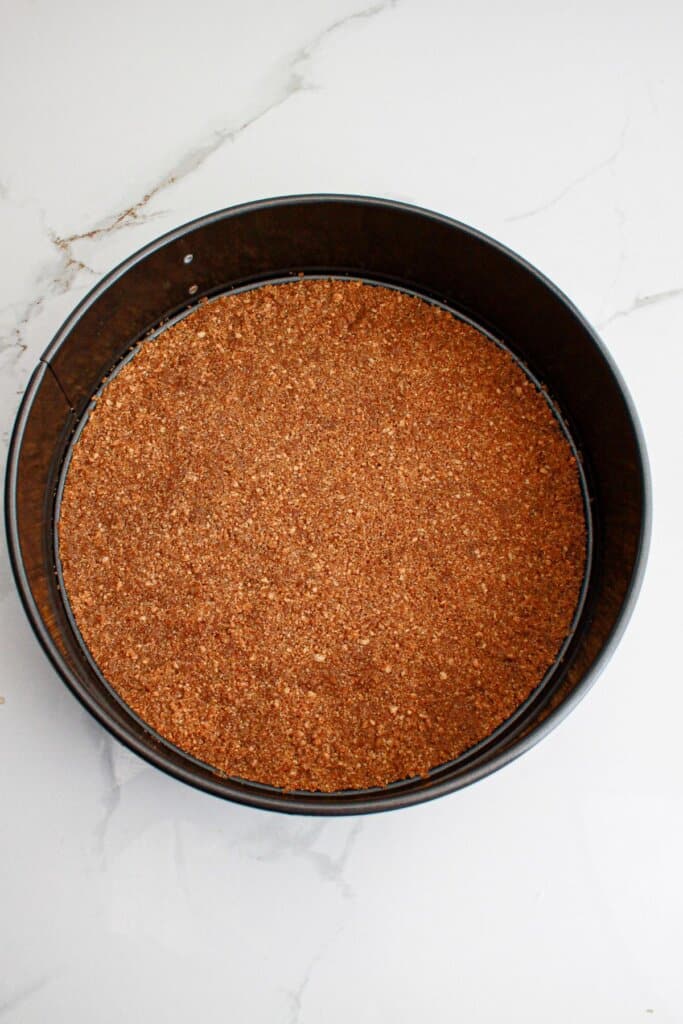 crust being pressed into a springform pan.
