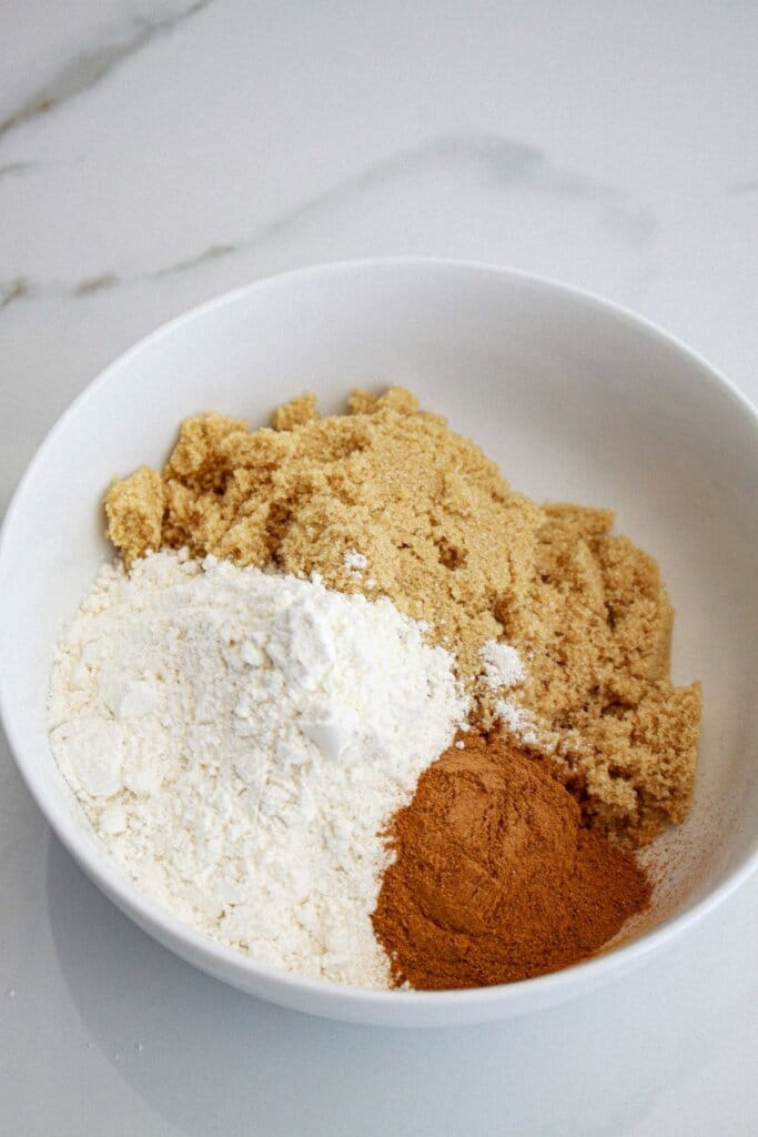 brown sugar, flour, and cinnamon being mixed in a small bowl.