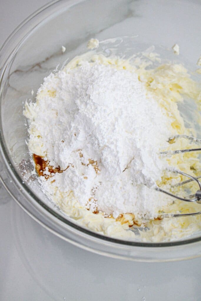 cream cheese, powdered sugar, and vanilla extract in a glass mixing bowl.