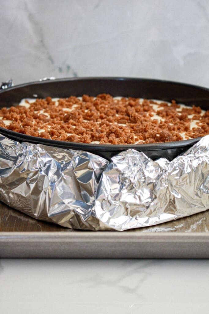 foil being added to the bottom of a cheesecake for a waterbath.