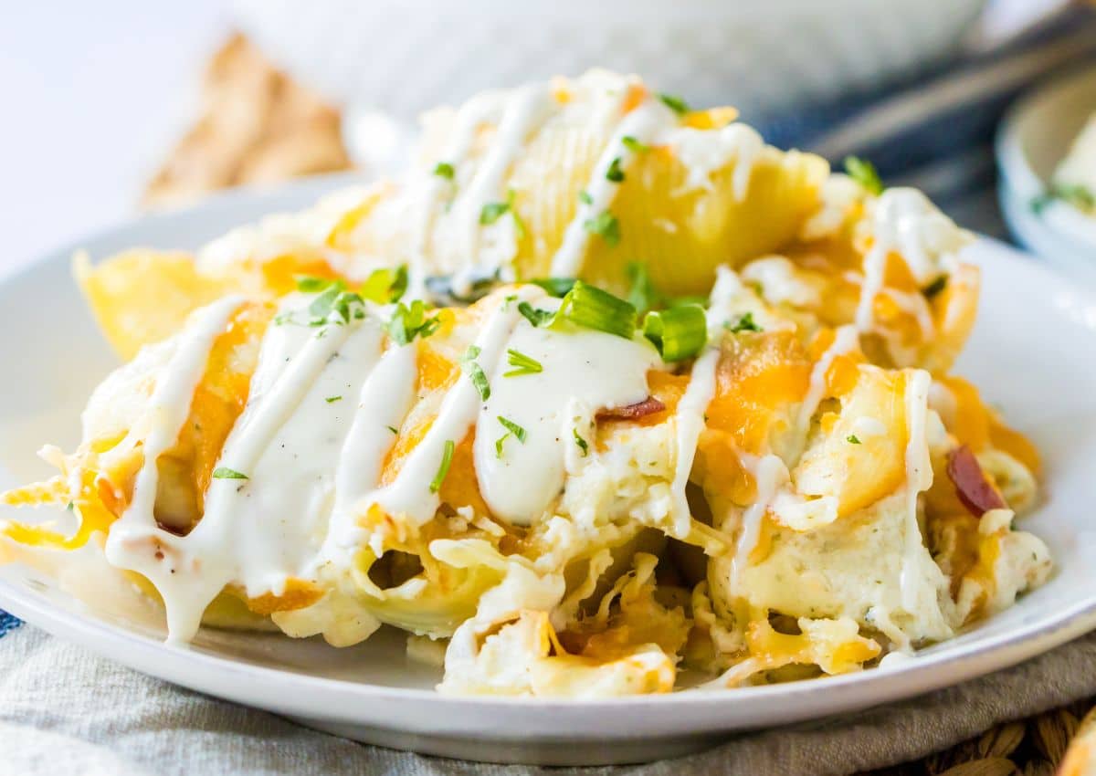 crack chicken stuffed shells on a plate topped with ranch dressing and green onions.