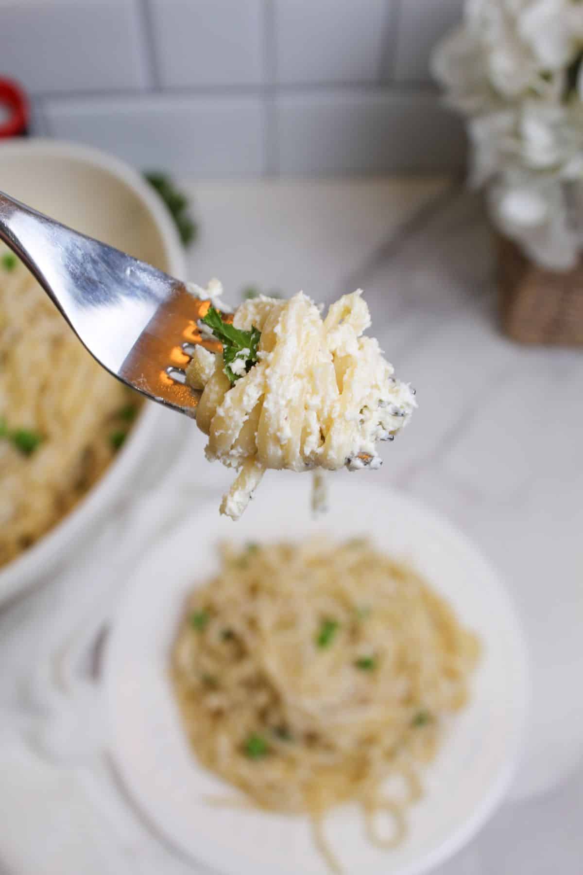 bite of cream cheese pasta held in the air on a fork.