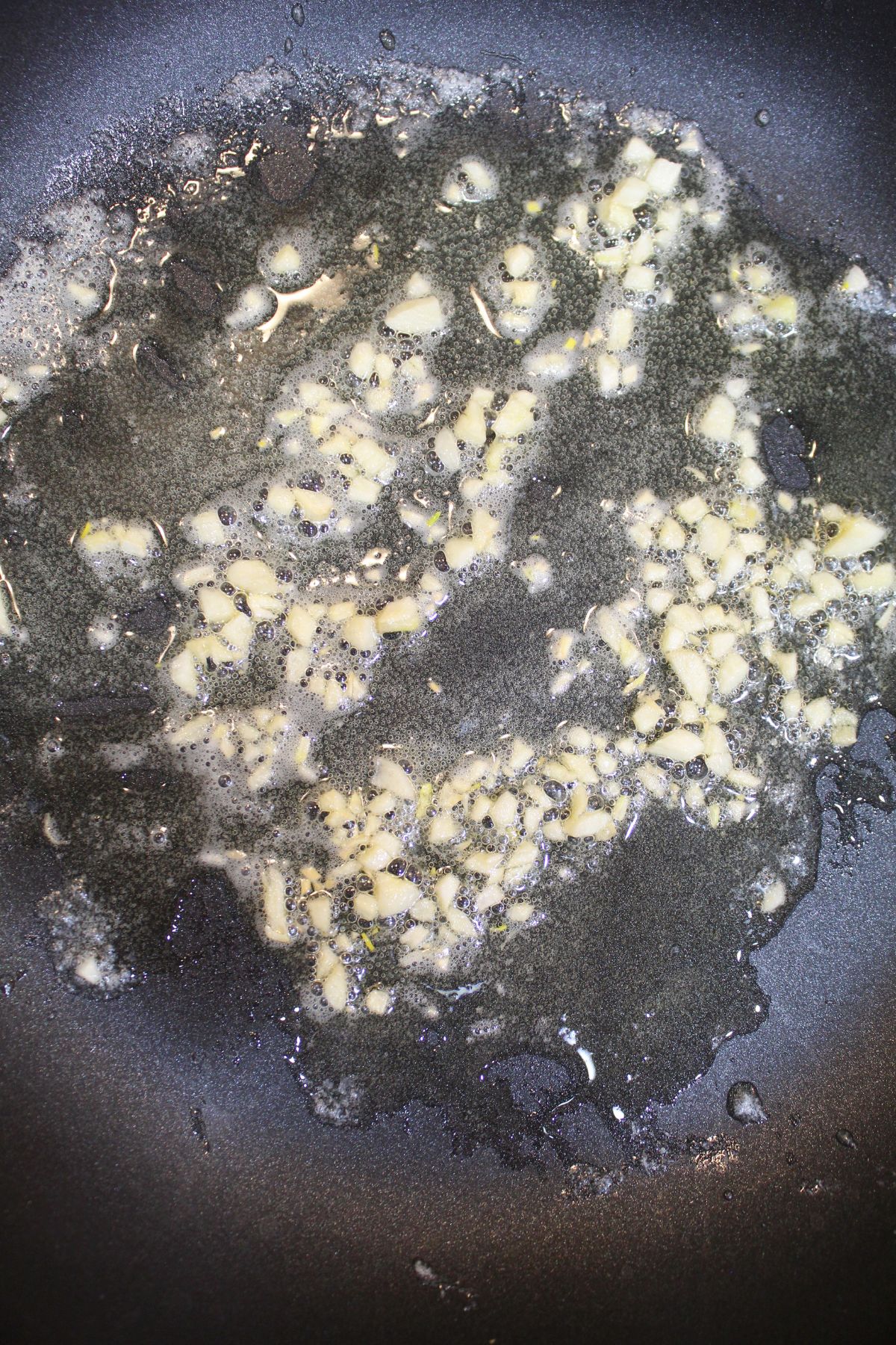 garlic being cooked in a melted butter in a skillet.