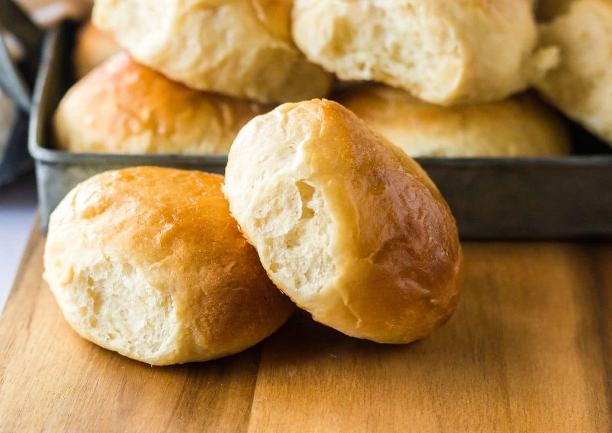 two homemade hawaiian rolls on a wooden cutting board.