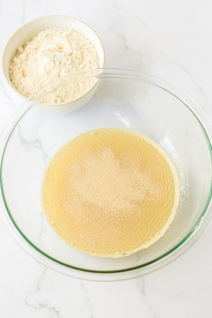 yeast, pineapple juice, and sugar in a glass mixing bowl.