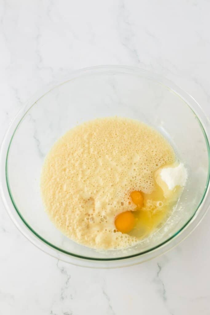 eggs being added to proofed yeast in a mixing bowl.