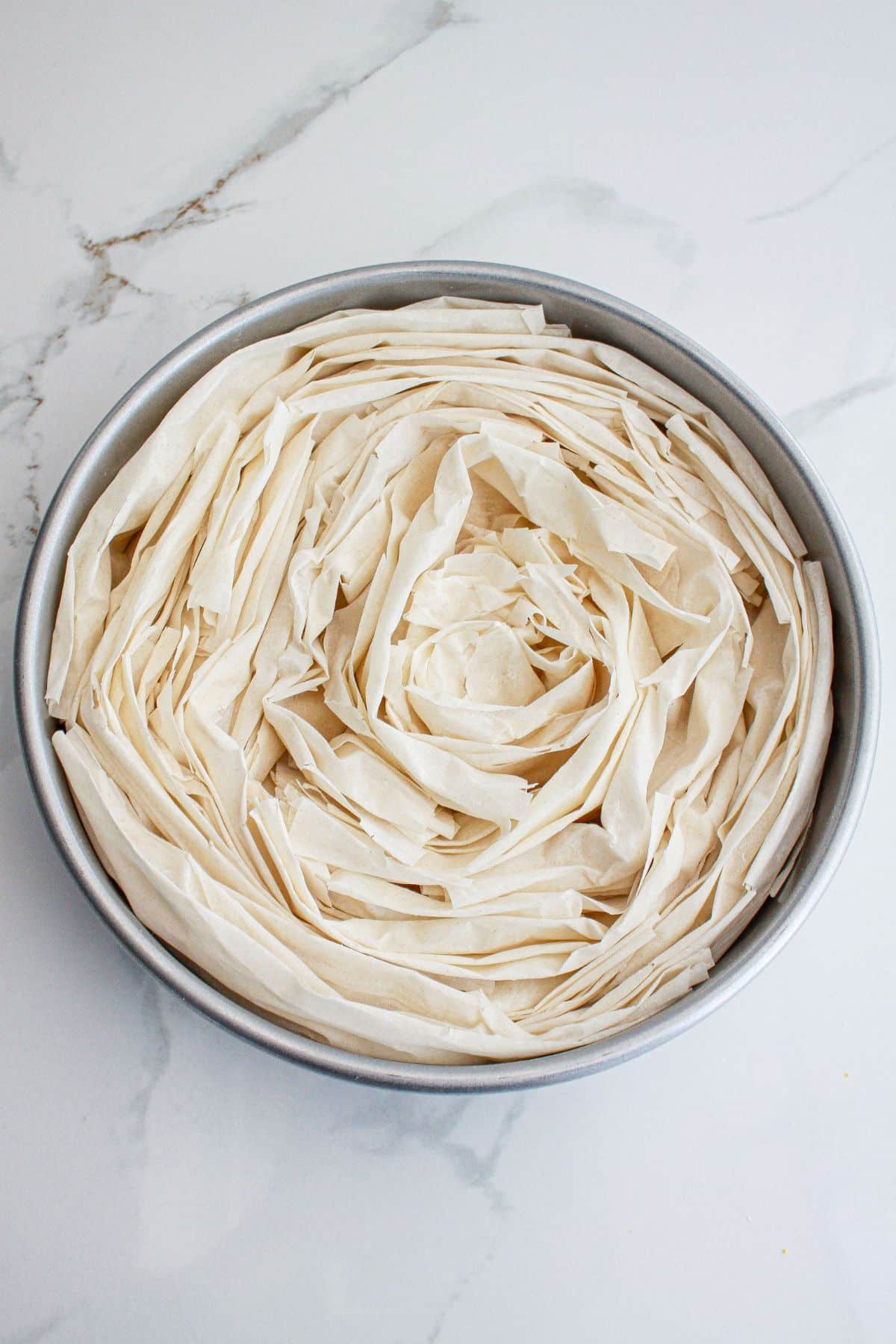 phyllo dough being crinkled in a cake pan.