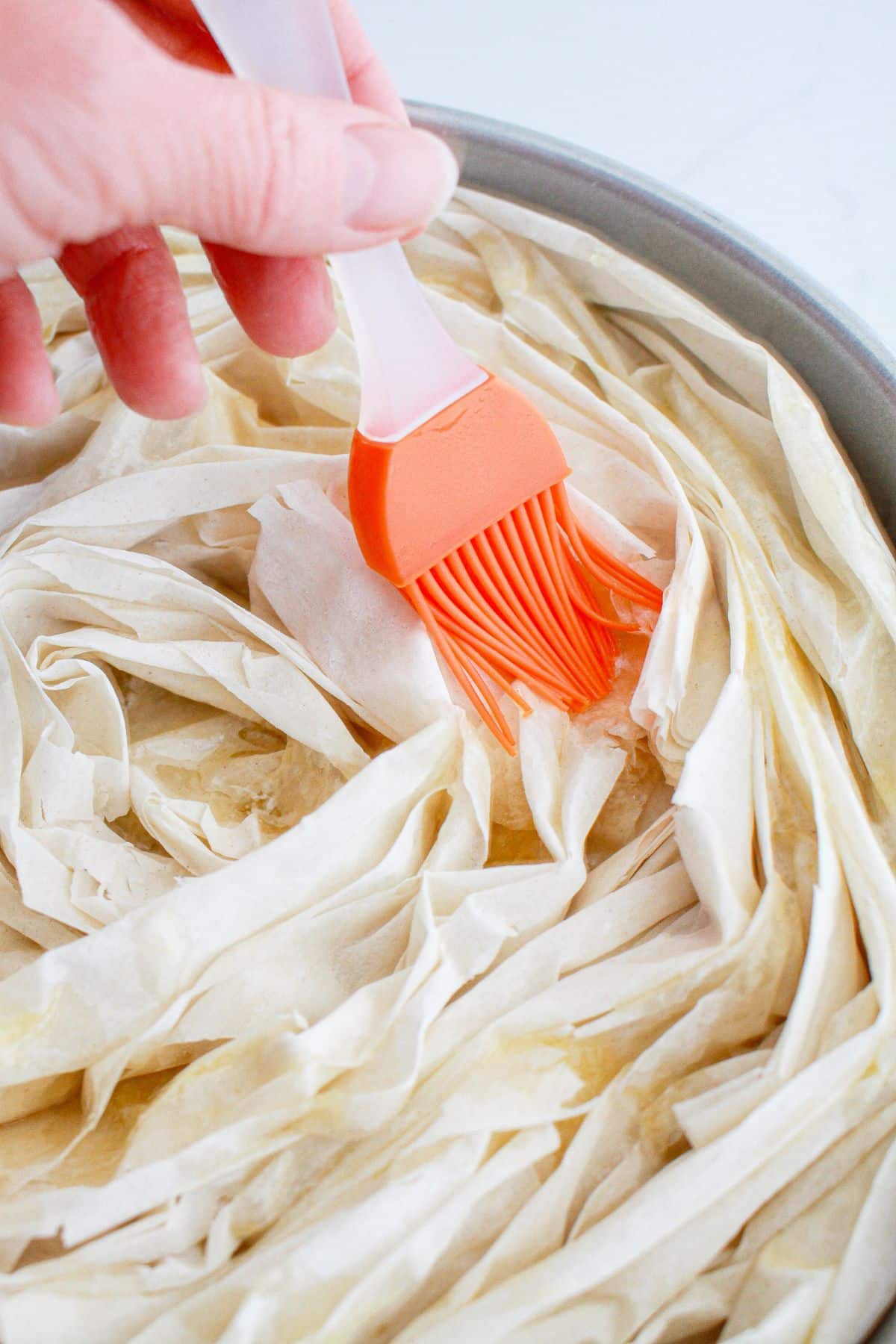 butter being brushed on top of pastry.
