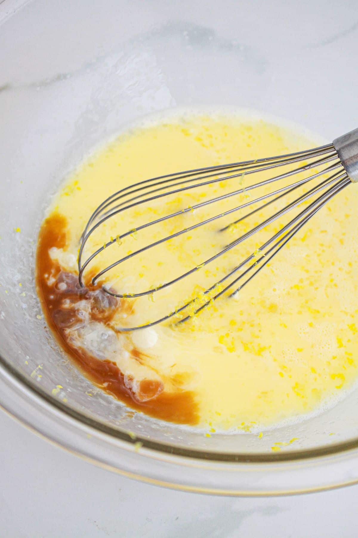 custard being mixed in a glass mixing bowl with a whisk.