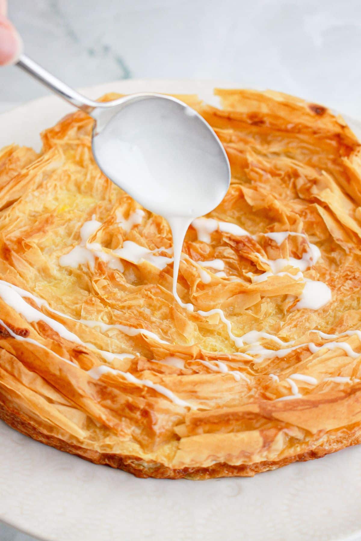 glaze being drizzled on top of the dessert with a spoon.