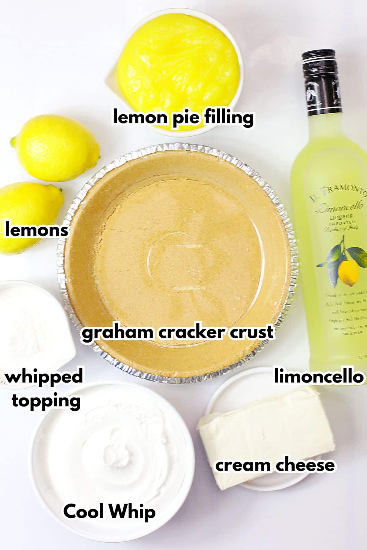 bowls of lemon pie filling, graham cracker crust, whipped topping, Cool Whip, cream cheese, lemons and limoncello on a counter.