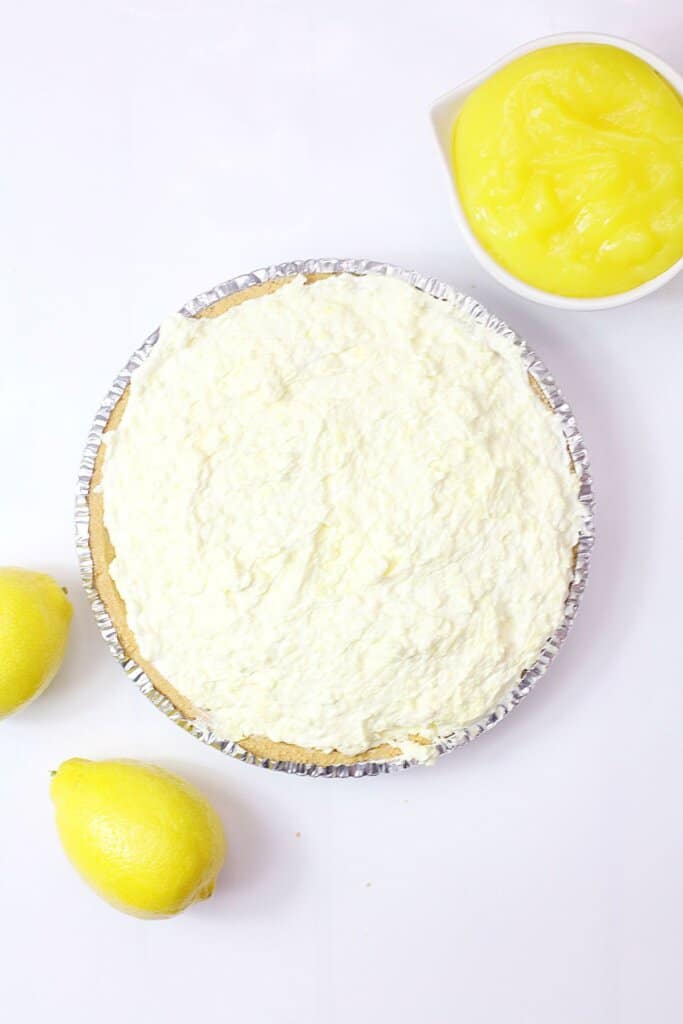 lemon pie filling being spread on top of a pie crust.