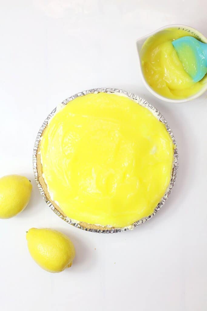 lemon pie filling being spread on top of a pie crust.