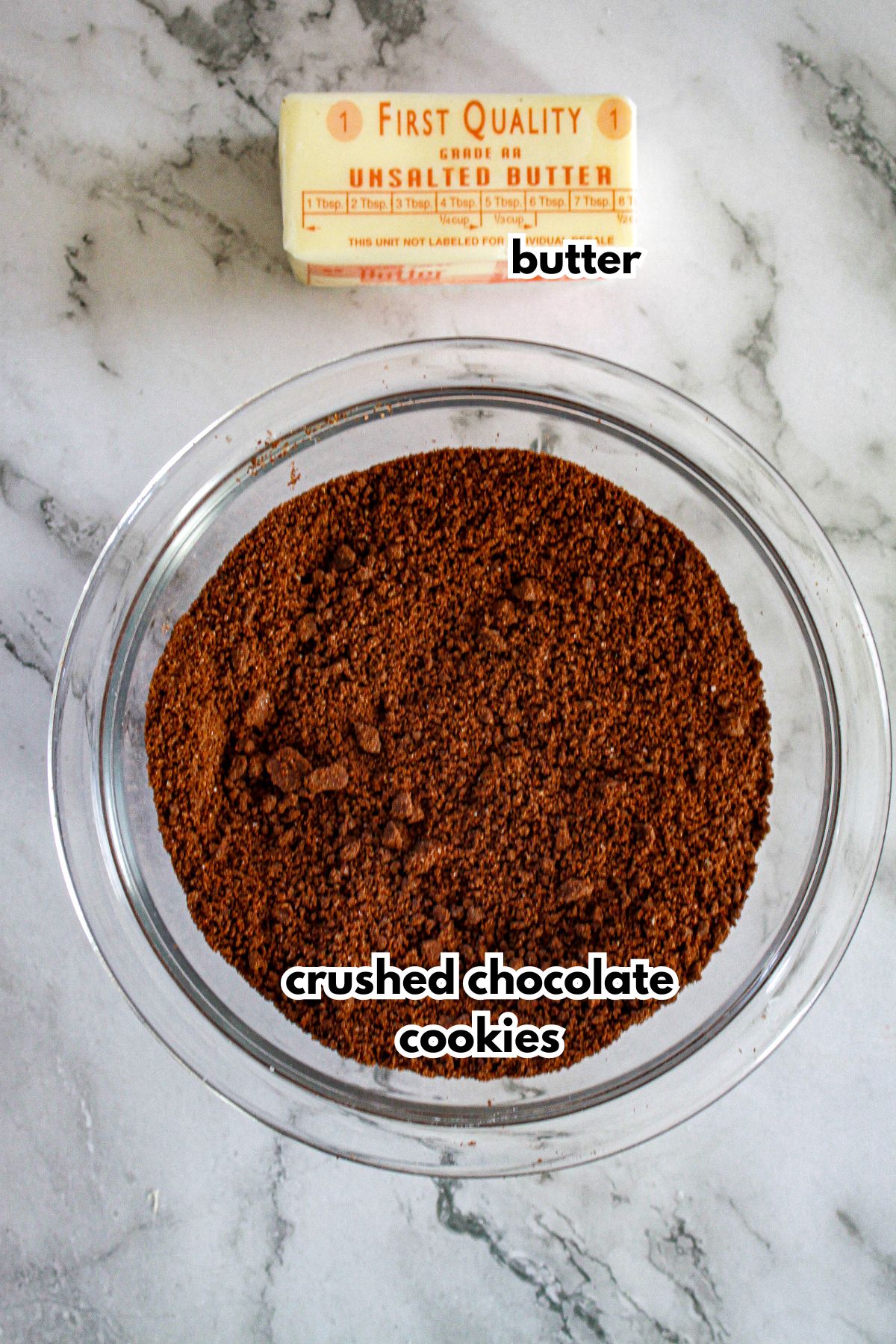 bowl of crush chocolate cookies and a stick of butter on a counter.