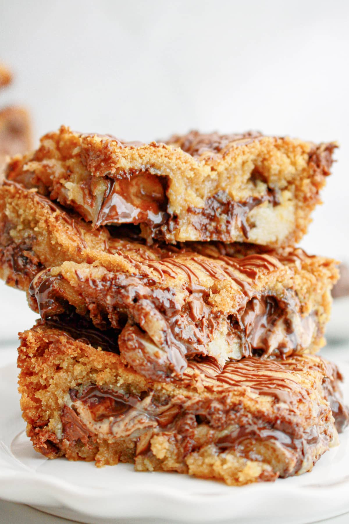 three peanut butter cup cookie bars stacked on a plate.