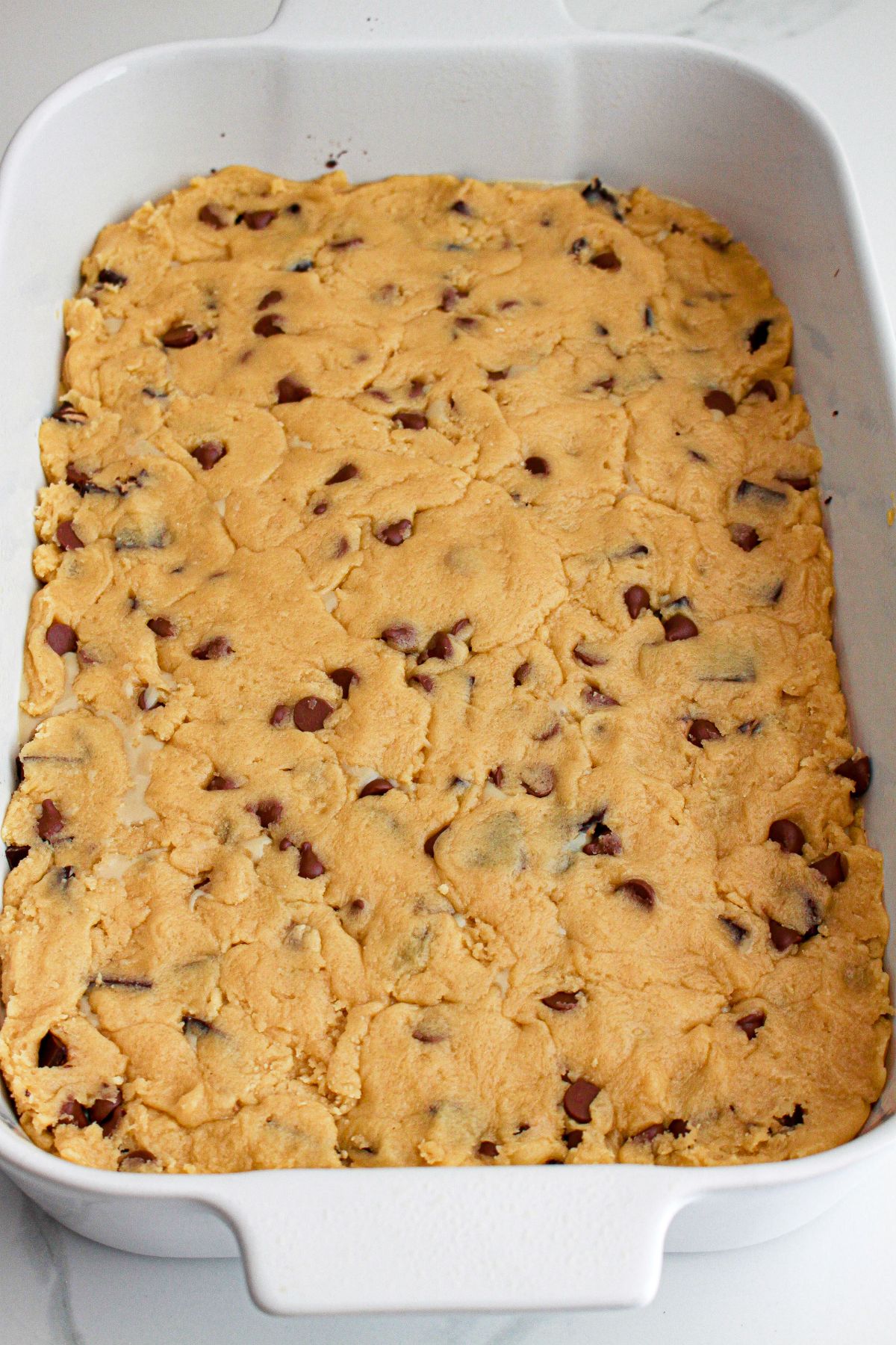 cooked dough being pressed into a baking dish.