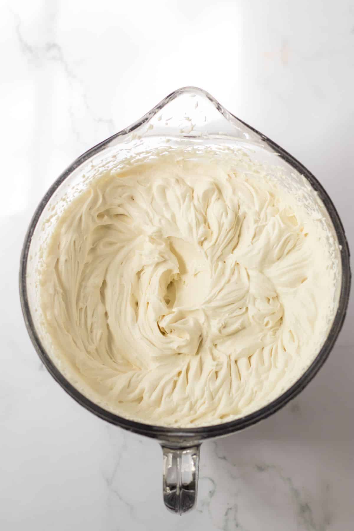 cream cheese filling being whipped in a mixing bowl.
