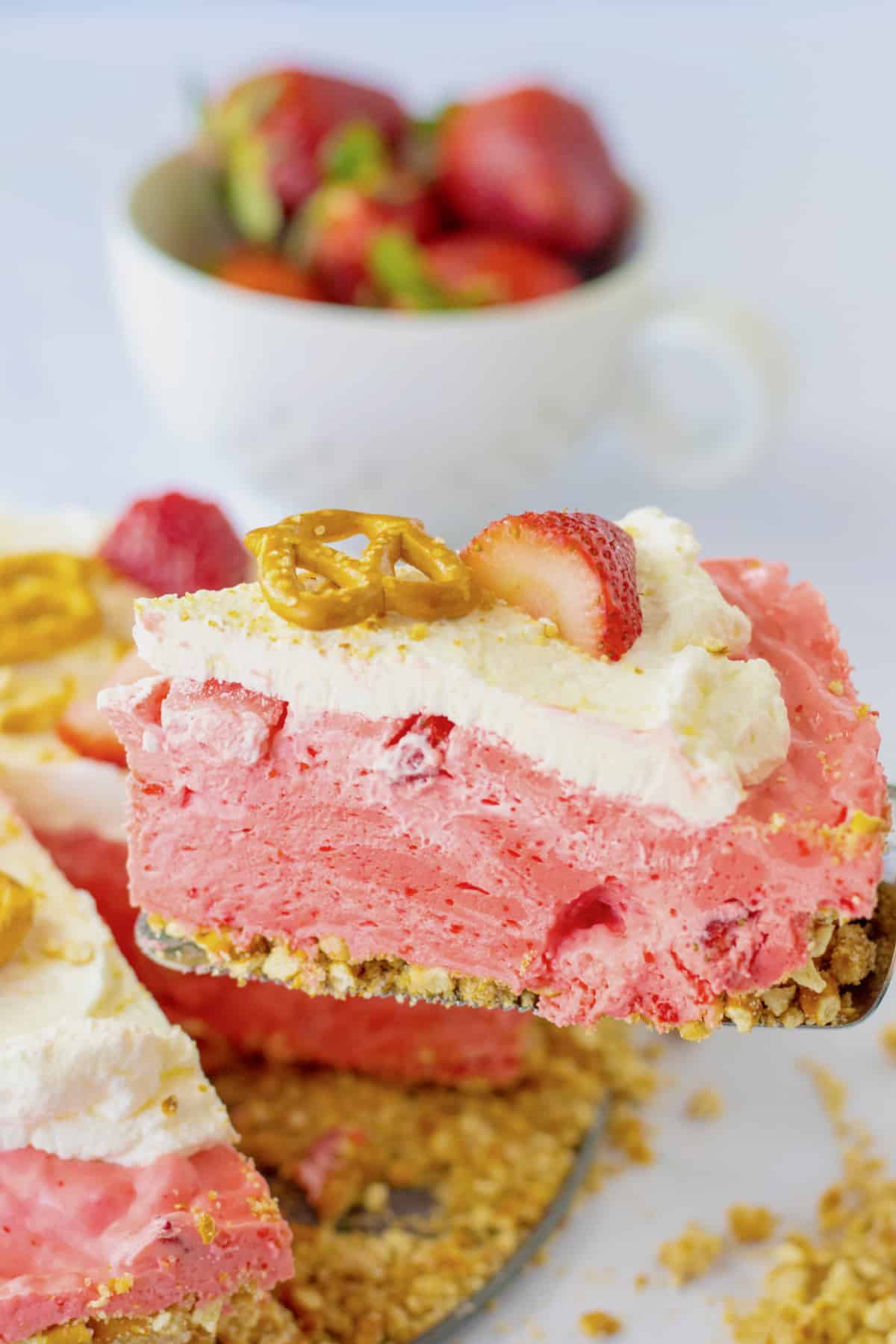 slice of strawberry pretzel pie being removed from the pie.