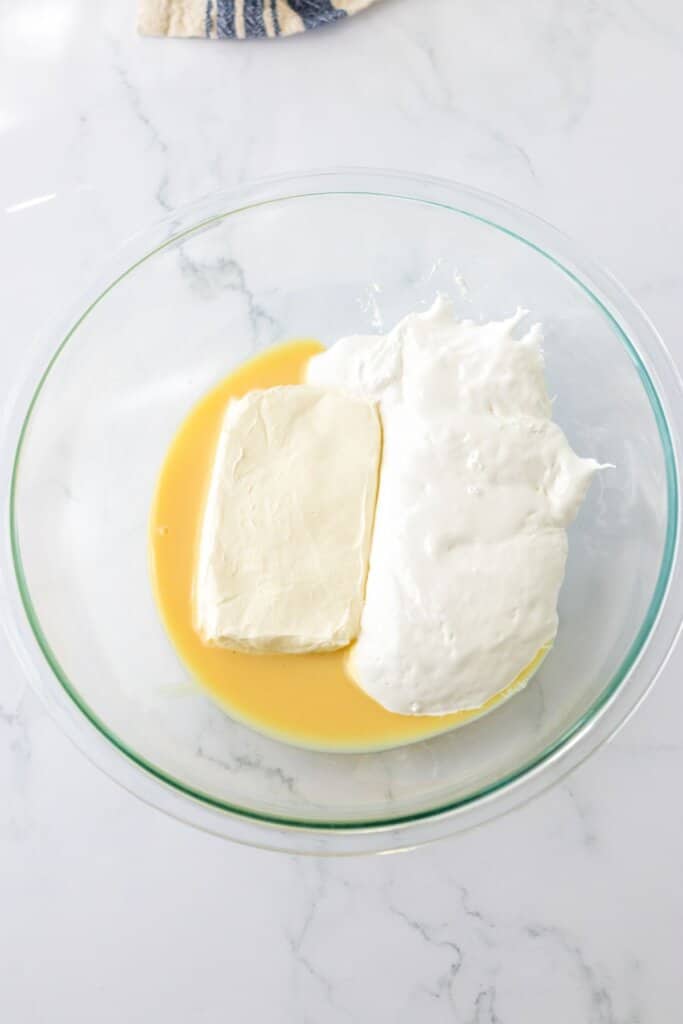 cream cheese being mixed in a glass bowl.