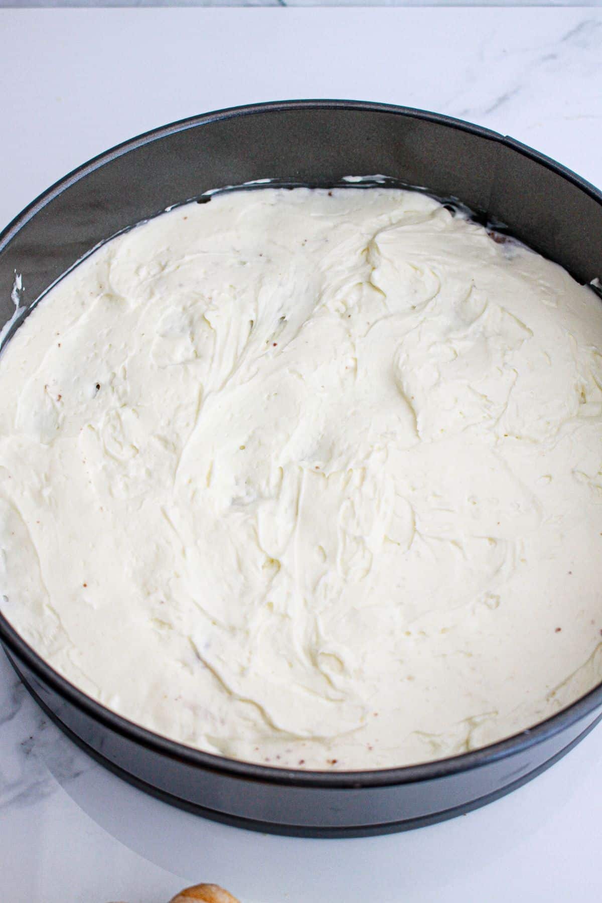 cheesecake layer being spread into a springfoam pan.