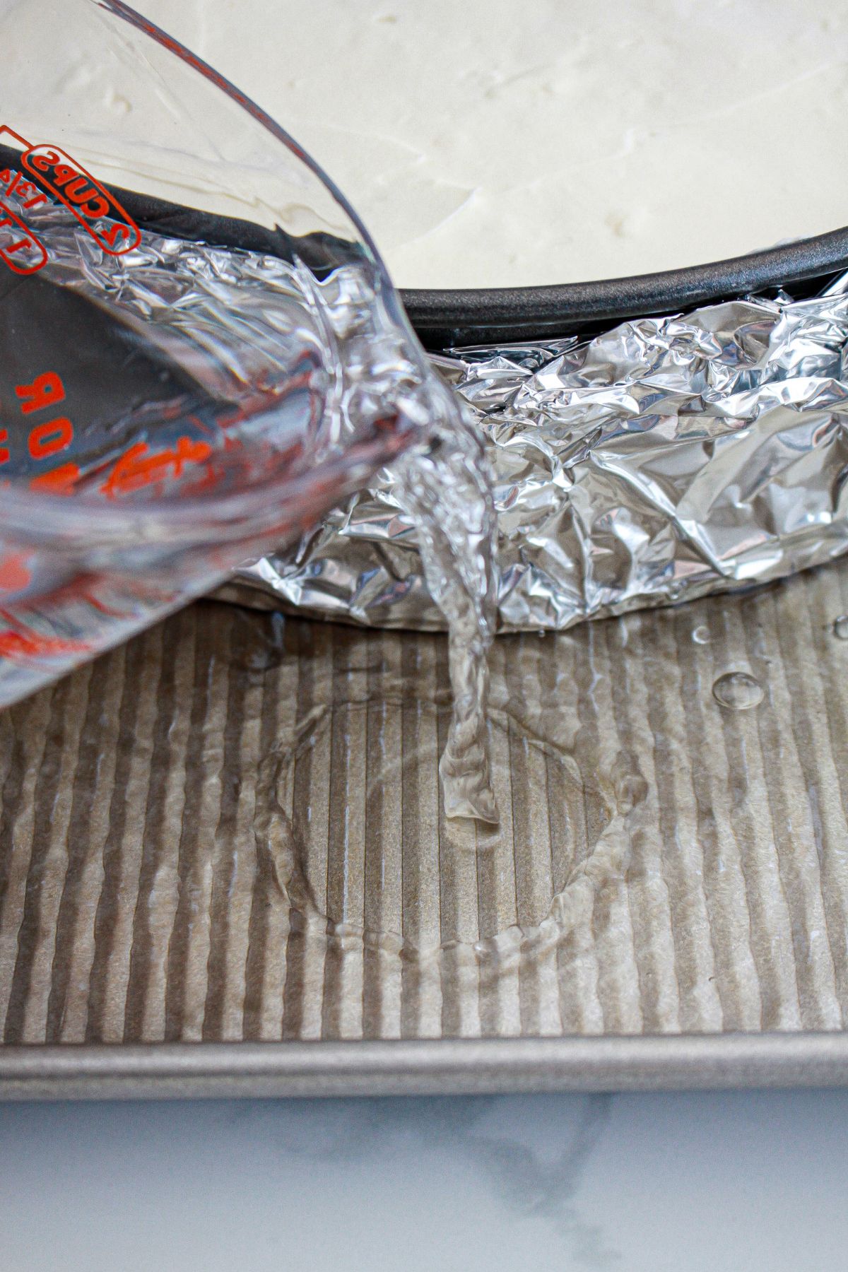 water being added to a pan for a water bath.