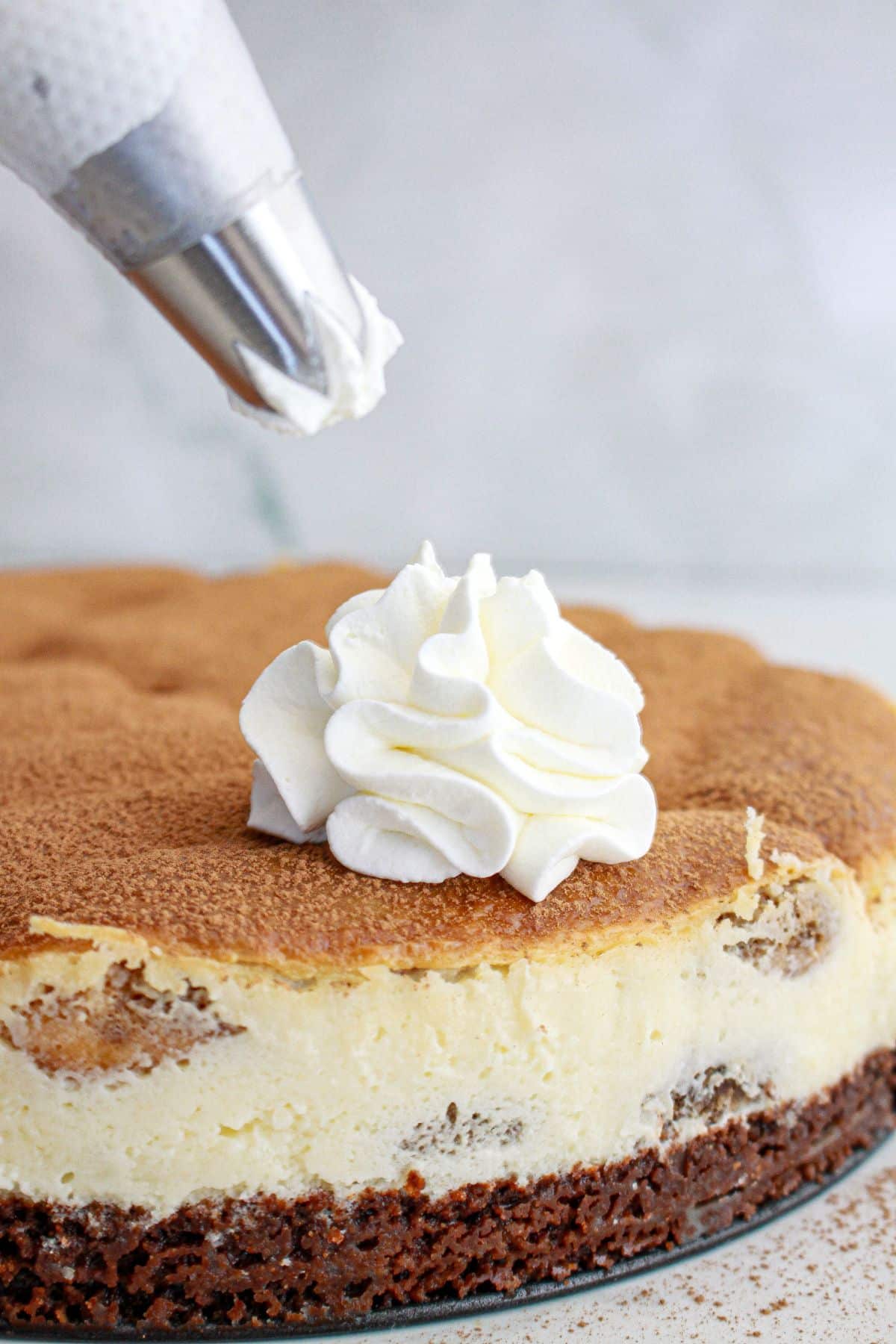 whipped cream being added to the top of the cheesecake.
