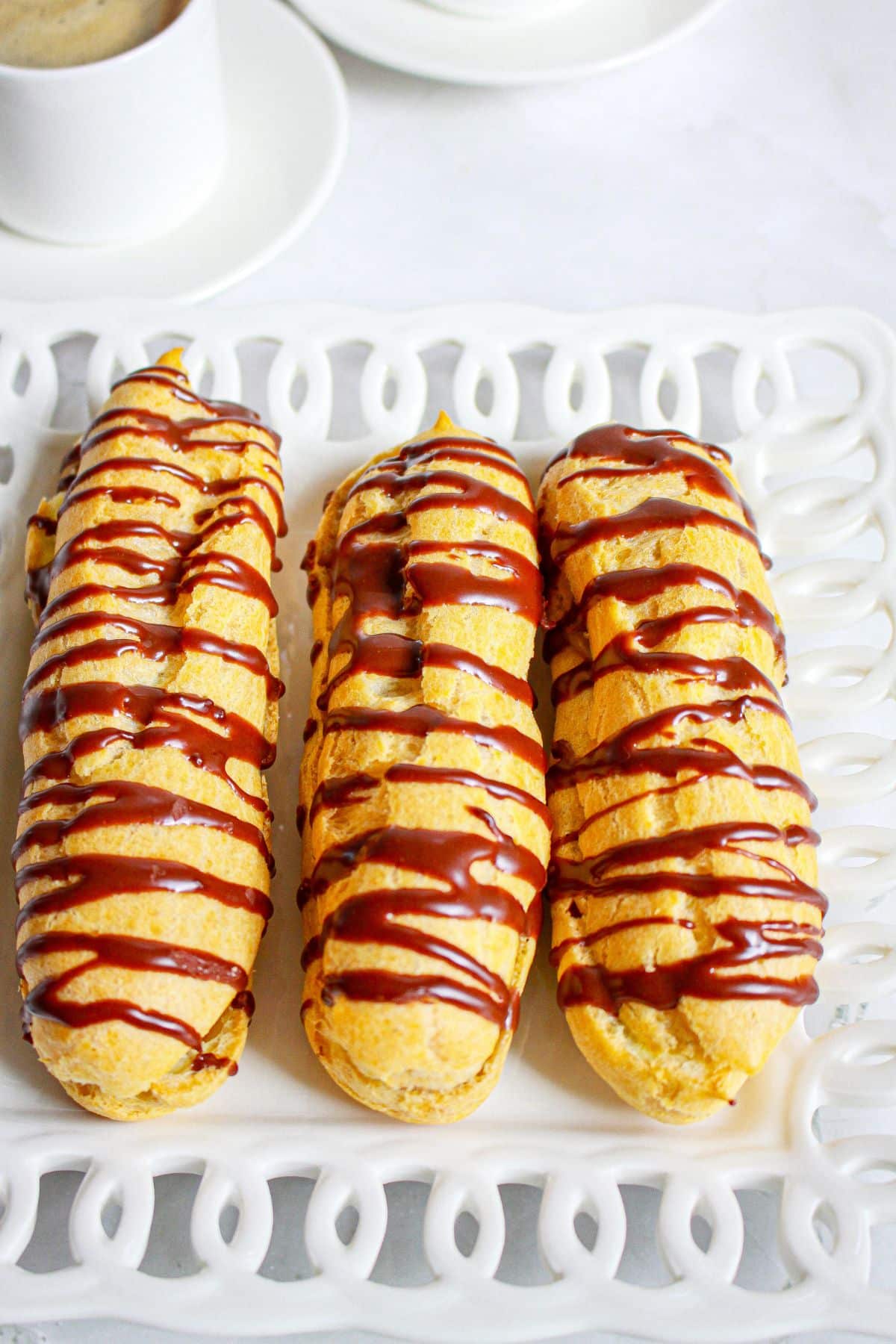 three cappuccino eclairs on a plate.