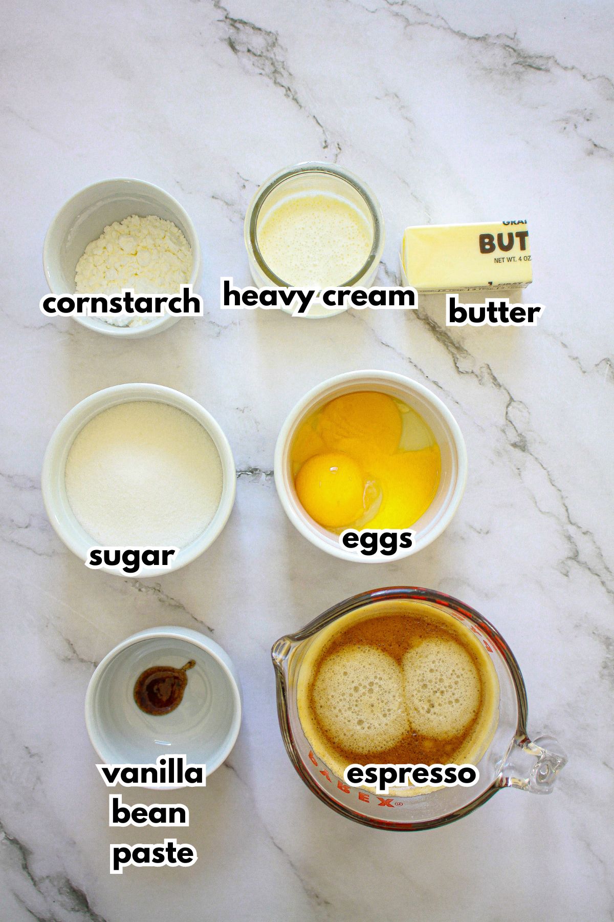 bowls of cornstarch, heavy cream, butter, sugar, eggs, vanilla bean pasta, espresso on a counter.