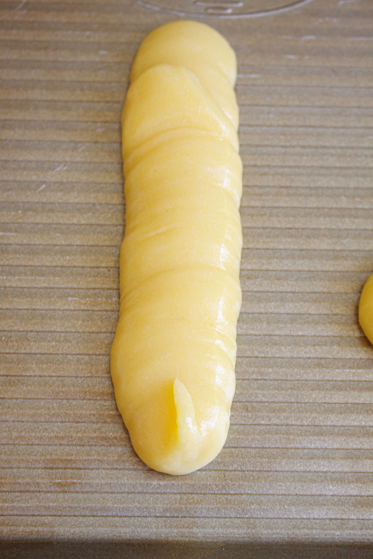 dough piped into a long shape on a baking sheet.