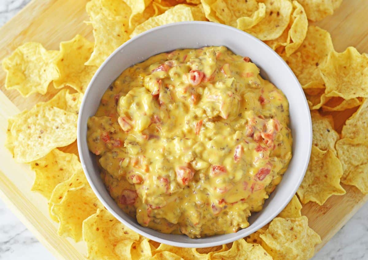 bowl full of cheese and rotel dip surrounded by tortilla chips.