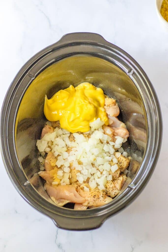 chicken, onions, seasonings, and cream of chicken soup added to crockpot.