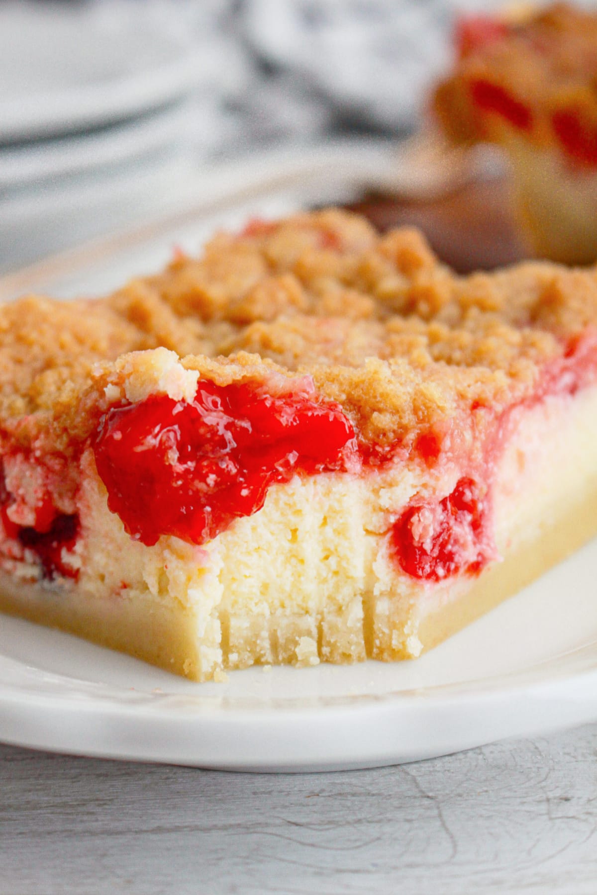 slice of cherry pie cheesecake bar on a plate with a bite missing.