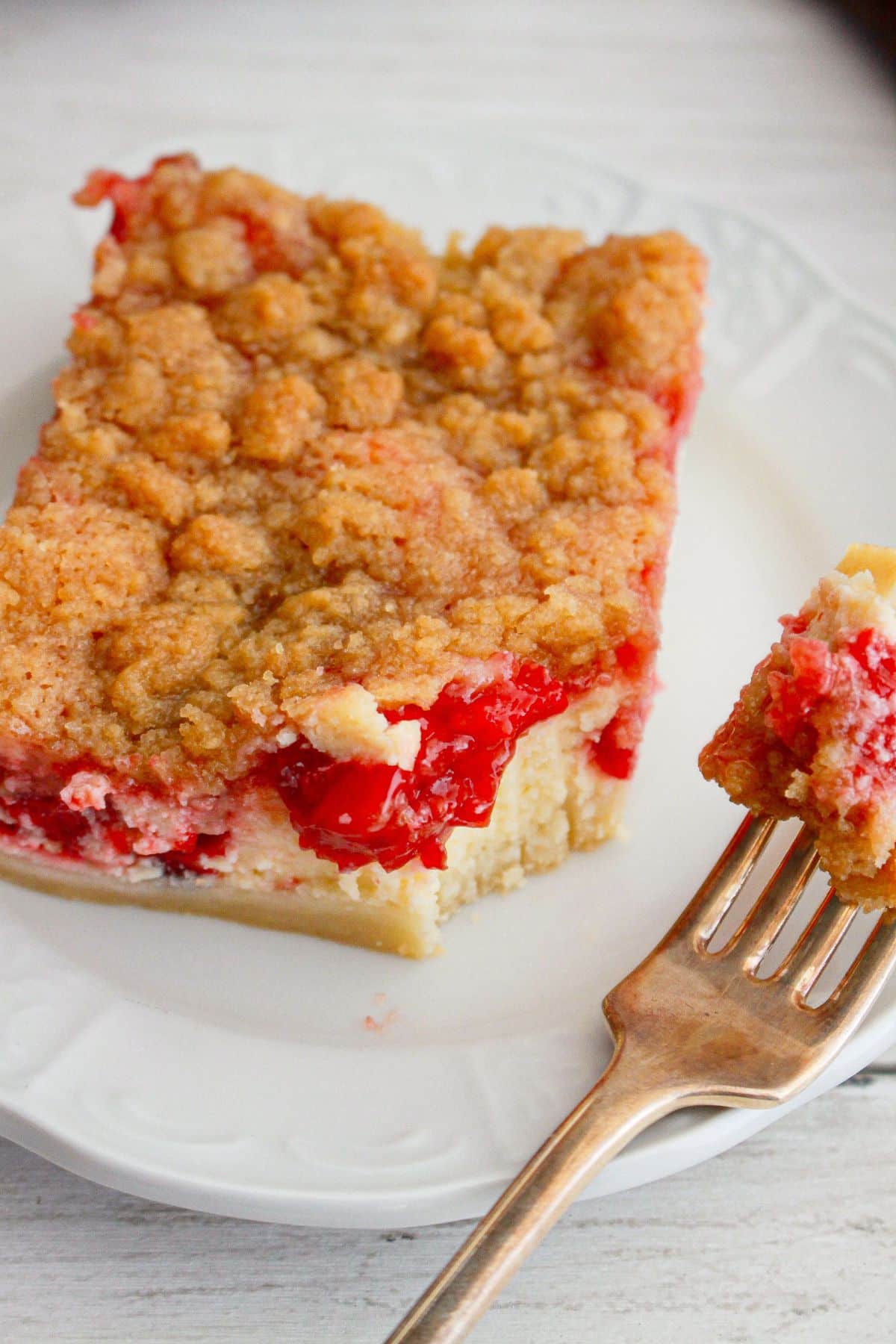 slice of cherry pie cheesecake bar on a plate with a bite missing.
