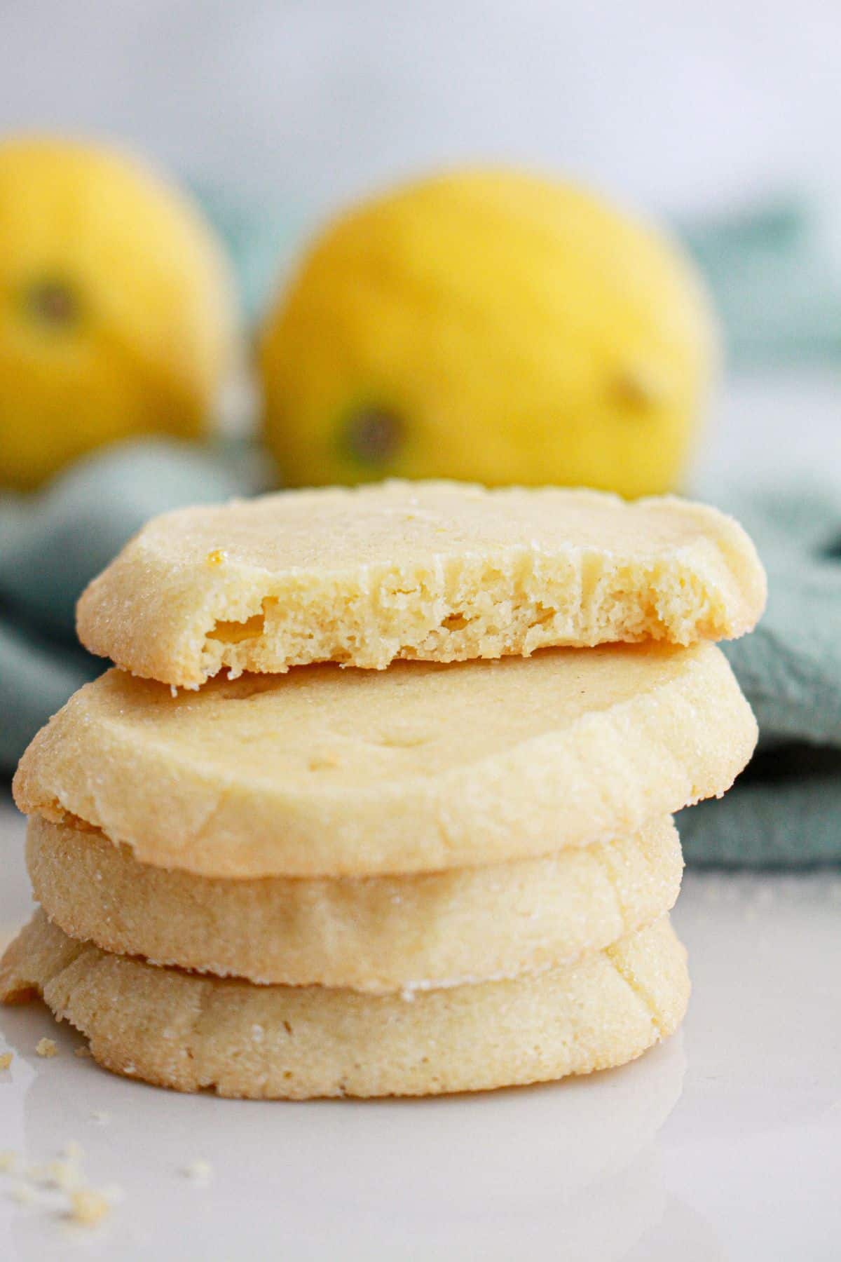 four french lemon butter cookies stacked on top of each other. The top one bitten in half.