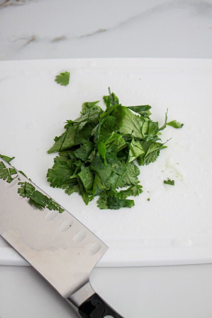 cilantro being chopped on a cutting board.