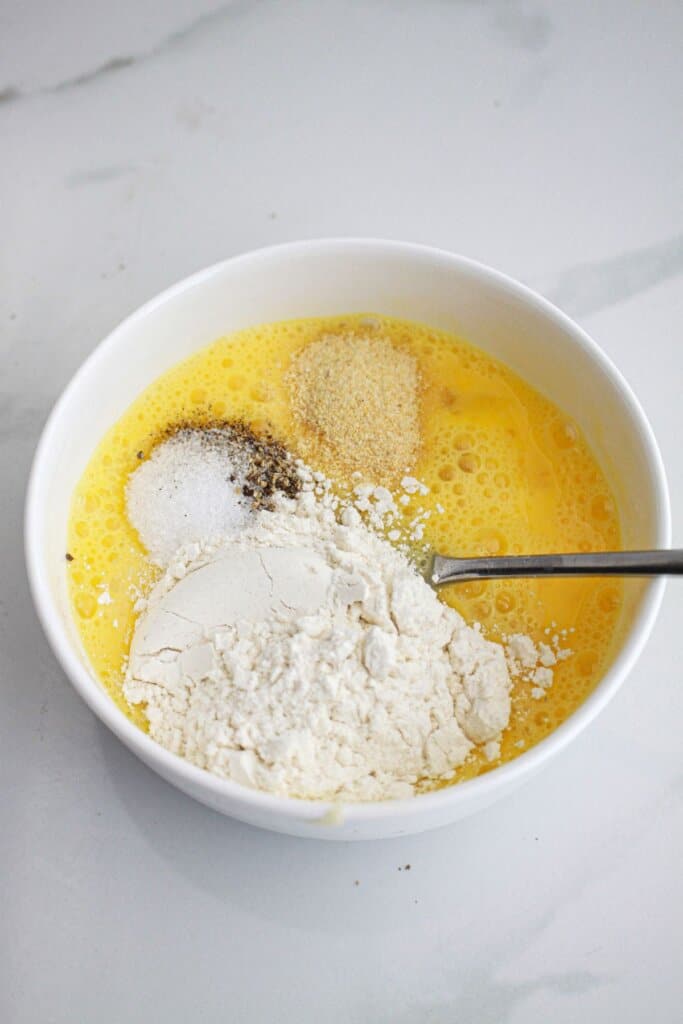 flour being added to two beaten eggs in a small bowl.