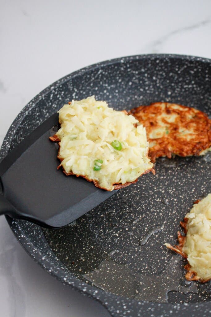 potato pancakes being cooked in a skillet.