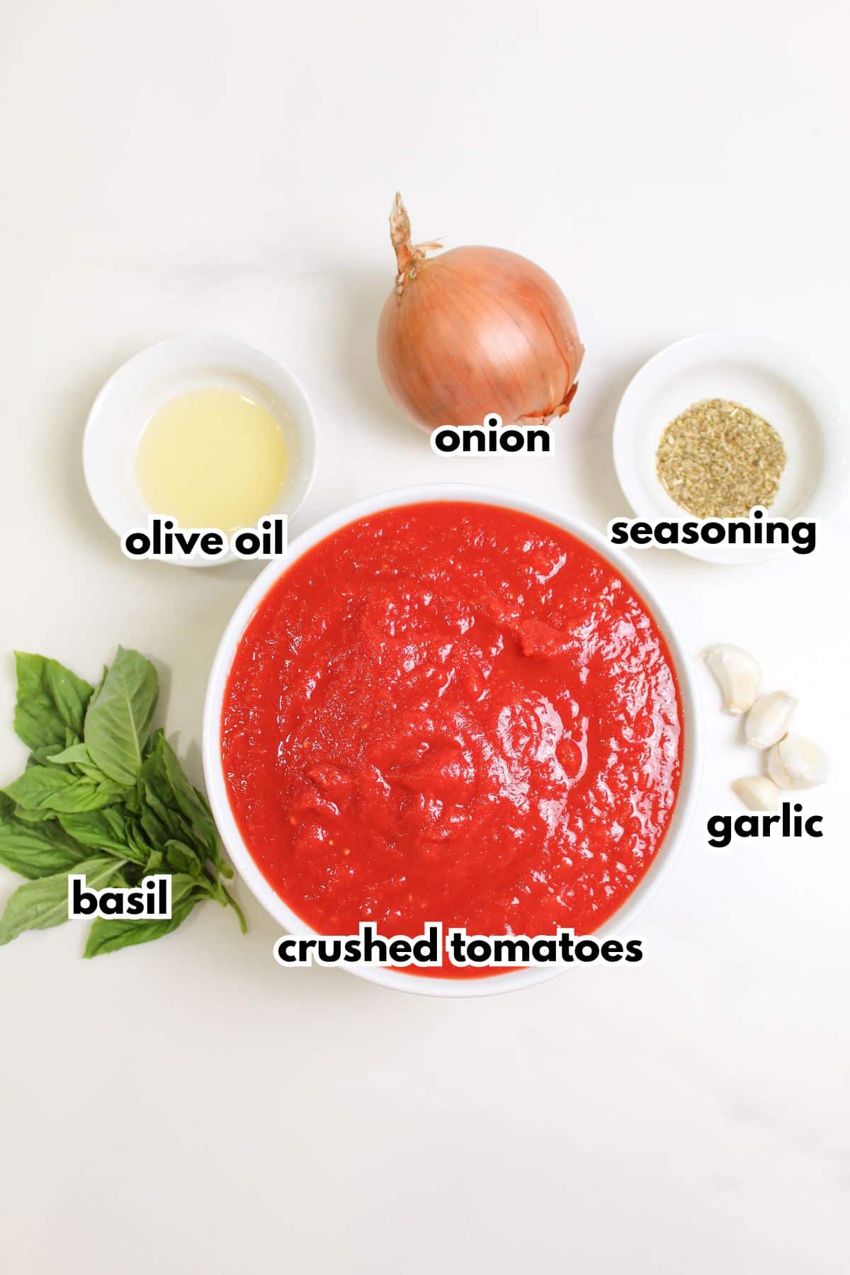 bowls of olive oil, onion, seaosning, basil, crushed tomatoes, and garlic on a counter.