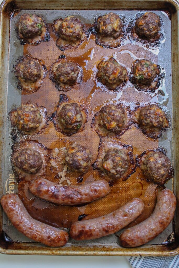 meatballs and italian sausage on a large baking sheet.