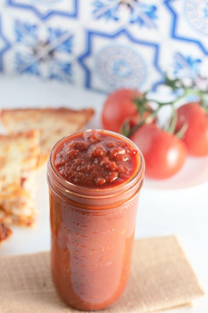 jar of homemade pizza sauce on a counter.